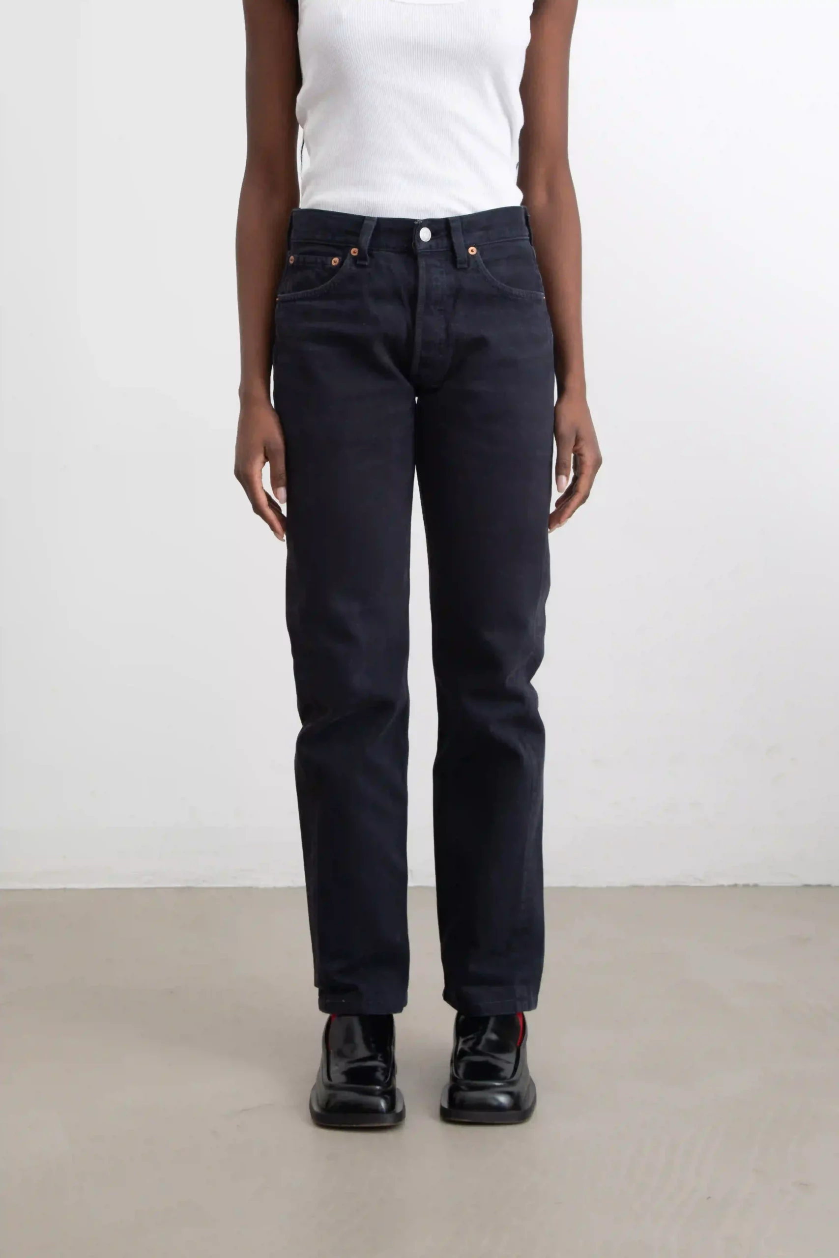Classic and timeless Levi's model 501 vintage denim pants in black drill, dark wash. Strong black stitching. Five pockets. At the end of the right back pocket is the iconic red Levi's tab.