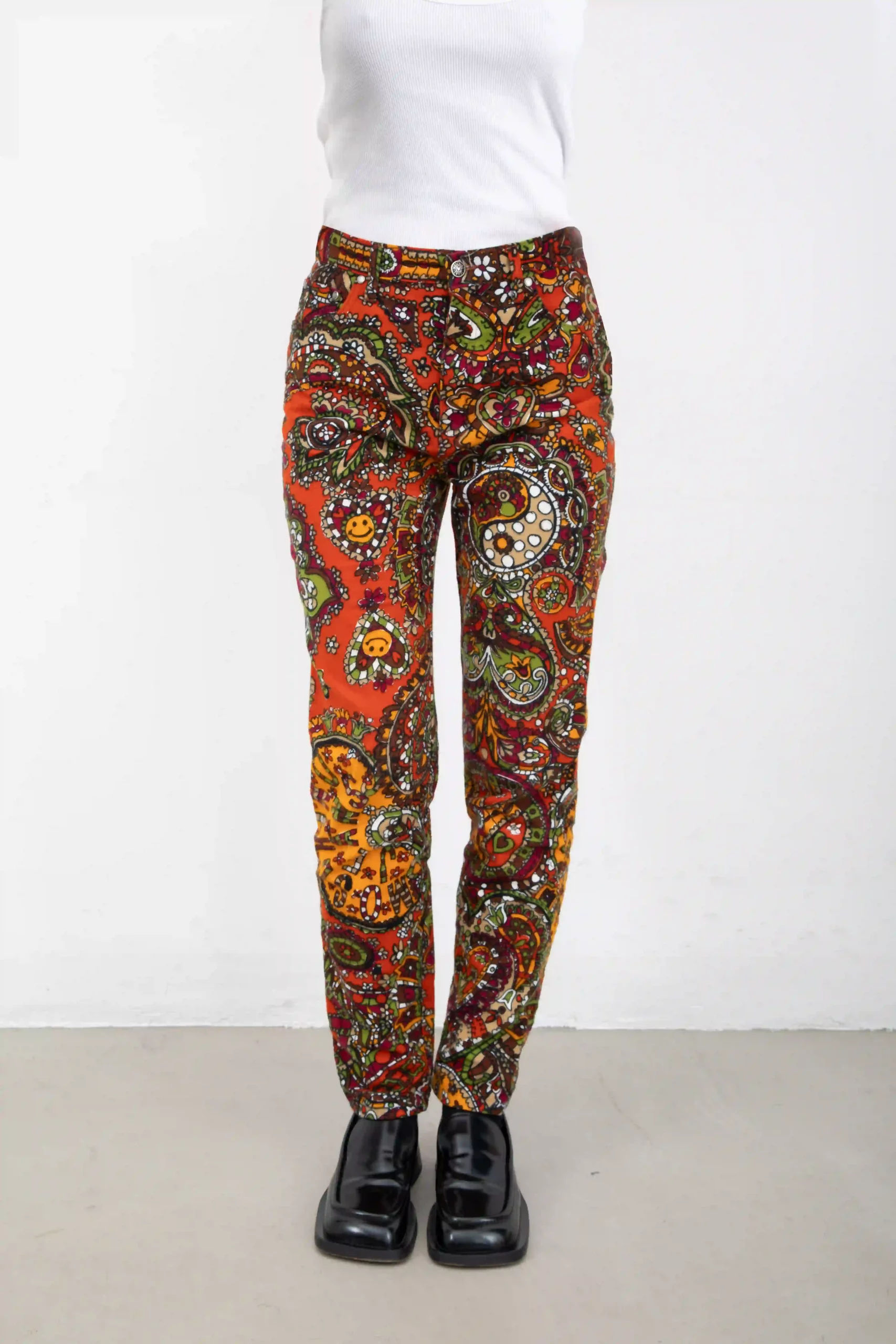 Pantalone Moschino Jeans multicolor sui toni mattone, in 100% cotone stampato ad effetto velluto. Motivo floreale, con smile, molto hippie e divertente. Modello a sigaretta, tipo jeans. Con patch in metallo simbolo della pace sulla tasca posteriore.